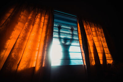 Low angle view of sunlight streaming through window in dark room