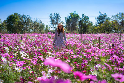 Woman standing by pink flowers on field
