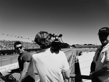 Rear view of people photographing against clear sky