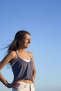 Smiling woman standing against blue sky