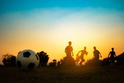 People playing soccer at sunset