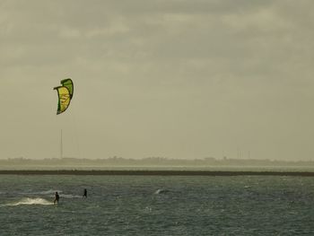 People kiteboarding in sea against sky