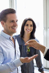 Cropped image of real estate agent handing over keys to couple in new house