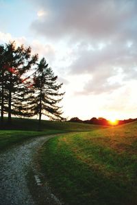 Scenic view of grassy field against sky during sunset