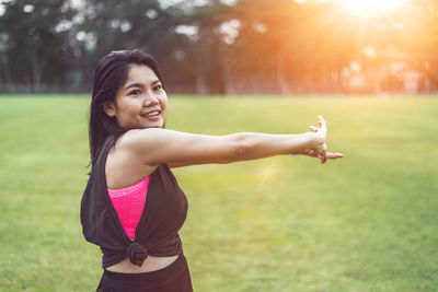 Portrait of smiling young woman standing on field