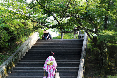 Rear view of japanese woman walking on steps in park