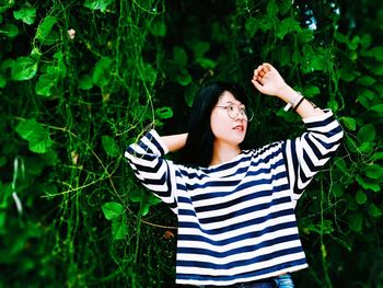 Beautiful young woman standing against plants