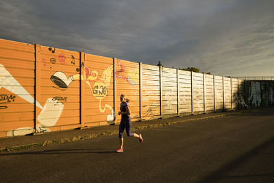 Rear view of woman running on road against sky