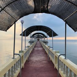 Empty walkway by sea against sky