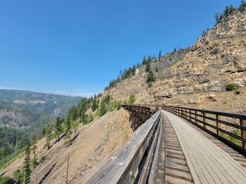 Road leading towards mountain against clear blue sky