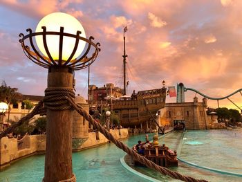 Close-up of illuminated lighting equipment in amusement park during sunset