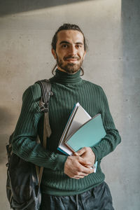 Portrait of young man standing against wall