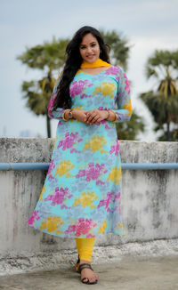 Portrait of young woman standing against wall