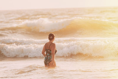 Rear view of woman standing at beach