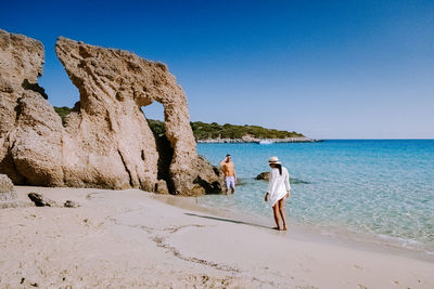 People on beach against clear blue sky