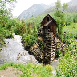 Built structure by trees on mountain against sky