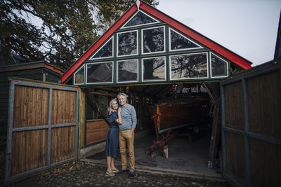 Senior couple standing in front of boathouse