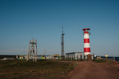 Lighthouse by sea against clear sky