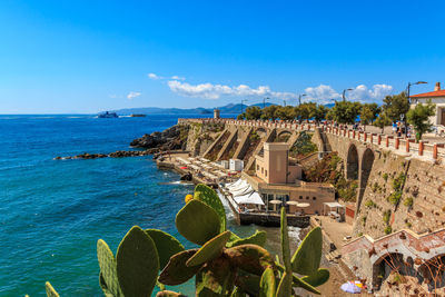 Panoramic view of sea and buildings against blue sky