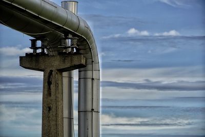 Low angle view of pipe by sea against sky