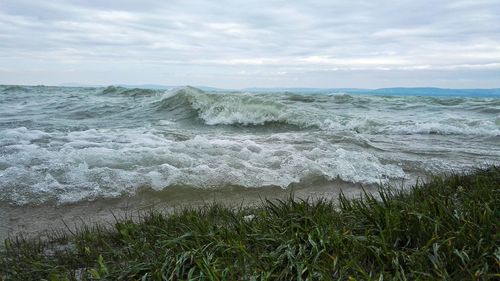 Waves in sea against cloudy sky