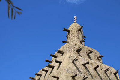 Low angle view of cross and building against clear blue sky
