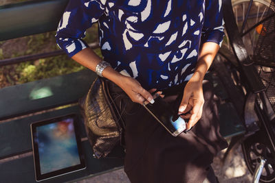 High angle midsection of businesswoman using smart phone while sitting on park bench