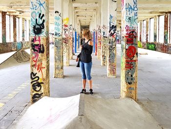 Full length rear view of woman walking on footpath against building