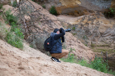 Rear view of man photographing on rock