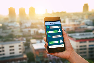 Hand holding smart phone against cityscape