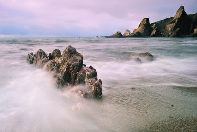 Scenic view of rocks in sea against sky