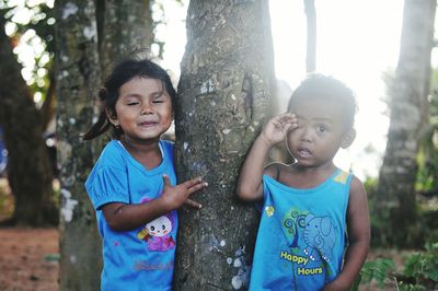 Portrait of siblings standing by tree