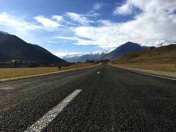 View of empty road by field against sky