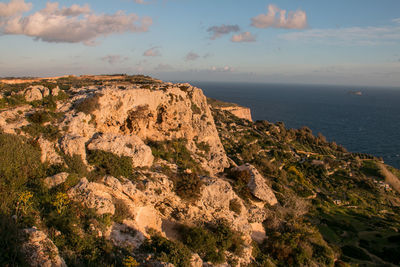 Rock formations by sea against sky