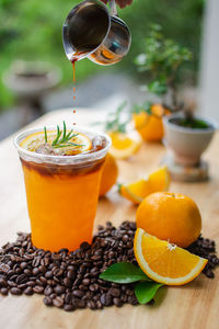 Black coffee top on fresh orange juice on wooden table