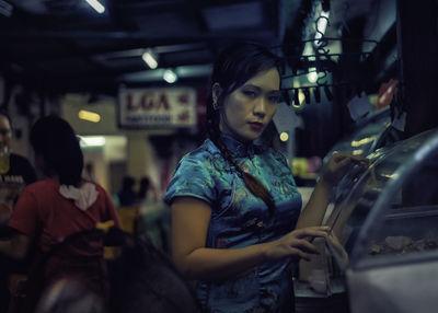 Portrait of woman standing against display cabinet in store