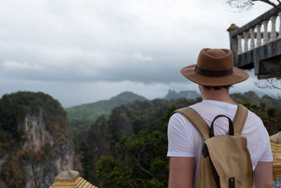 Rear view of man standing by mountain against sky