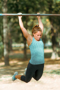 Woman exercising on horizontal bar outdoors in the fall, in public park