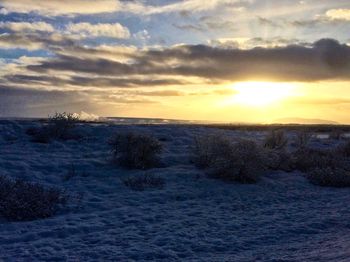 Scenic view of snow covered land during sunset