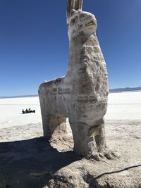 Stone wall on beach against clear blue sky