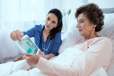 Friends looking away while relaxing on bed