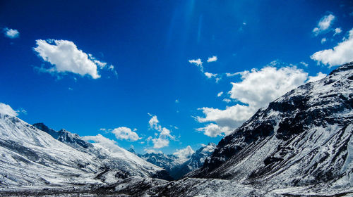 Scenic view of snowcapped mountains against blue sky