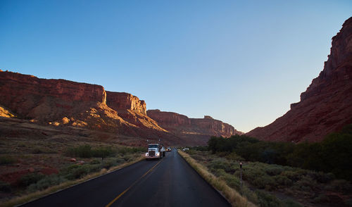 Road amidst mountains against clear sky