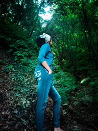 Side view of woman standing in forest