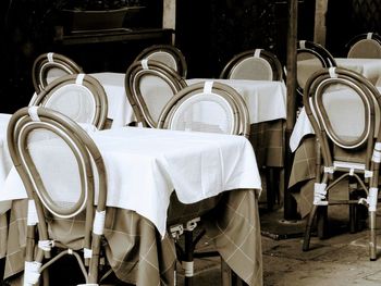 Close-up of chairs and table at sidewalk cafe in city