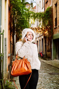 Woman wearing jacket talking on phone in city