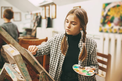 Young woman looking away while sitting on table