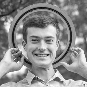 Portrait of smiling man holding ring behind head