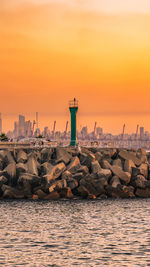 Lighthouse by sea against sky during sunset