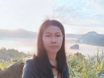 Portrait of beautiful young woman standing on mountain against sky
